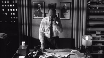 Movie still from “Shock Corridor” (1963), directed by Samuel Fuller – A man talking on a phone in a room; Medium shot, Low angle