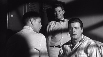 Movie still from “Shock Corridor” (1963), directed by Samuel Fuller – A group of men standing next to each other in a room; Medium shot, Over the shoulder angle