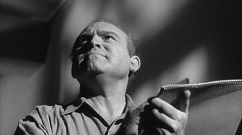 Movie still from “Shock Corridor” (1963), directed by Samuel Fuller – A man holding a pen in his hand and looking up; Close Up shot, Low angle