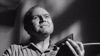 Movie still from “Shock Corridor” (1963), directed by Samuel Fuller – An older man holding a cell phone up to his face; Close Up shot, Low angle