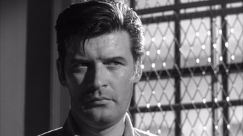 Movie still from “Shock Corridor” (1963), directed by Samuel Fuller – Black and white photograph of a man in front of a lattice window; Close Up shot, Low angle