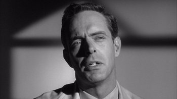 Movie still from “Shock Corridor” (1963), directed by Samuel Fuller – Black and white photograph of a man in a suit; Close Up shot, Low angle