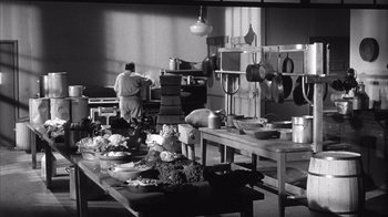 A black and white photo of a man cooking in a kitchen
