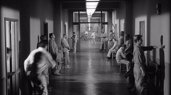 Movie still from “Shock Corridor” (1963), directed by Samuel Fuller – A black and white photo of a group of men sitting in a hallway; Extreme Wide shot, High angle