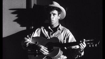 Movie still from “Shock Corridor” (1963), directed by Samuel Fuller – A man wearing a cowboy hat and holding a guitar; Close Up shot, Low angle
