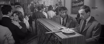 Movie still from “Shoot the Piano Player” (1960), directed by François Truffaut – A black and white photo of a man sitting at a bar; Medium shot, High angle