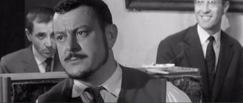 Movie still from “Shoot the Piano Player” (1960), directed by François Truffaut – A black and white photo of a man with a mustache; Close Up shot, Over the shoulder angle