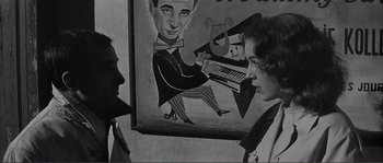 Movie still from “Shoot the Piano Player” (1960), directed by François Truffaut – A black - and - white photo of two people in front of a painting; Medium shot, Over the shoulder angle