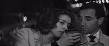 Movie still from “Shoot the Piano Player” (1960), directed by François Truffaut – A woman looking into a cell phone with lights in the background; Close Up shot, High angle