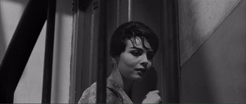 Movie still from “Shoot the Piano Player” (1960), directed by François Truffaut – A black - and - white photo of a woman standing in front of bars; Close Up shot, Low angle