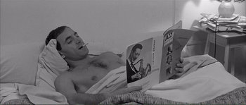 Movie still from “Shoot the Piano Player” (1960), directed by François Truffaut – A man reading a magazine while laying in bed; Medium shot, High angle