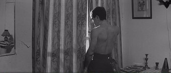 Movie still from “Shoot the Piano Player” (1960), directed by François Truffaut – A man standing in front of a window with his back turned; Medium shot, Low angle