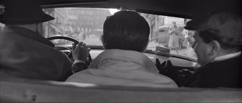 Movie still from “Shoot the Piano Player” (1960), directed by François Truffaut – A man driving a car on a street; Medium shot, Over the shoulder angle