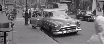 Movie still from “Shoot the Piano Player” (1960), directed by François Truffaut – An old photo of an old car on the street; Wide shot, High angle