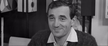 Movie still from “Shoot the Piano Player” (1960), directed by François Truffaut – A black - and - white photo of a man smiling for the camera; Close Up shot, High angle