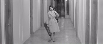 Movie still from “Shoot the Piano Player” (1960), directed by François Truffaut – A black and white photo of a woman in a trench coat holding an umbrella; Wide shot, High angle