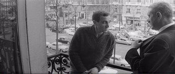 Movie still from “Shoot the Piano Player” (1960), directed by François Truffaut – A black and white photo of a man looking out a window; Medium shot, Low angle