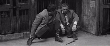 Movie still from “Shoot the Piano Player” (1960), directed by François Truffaut – A couple of men sitting next to each other on the ground; Medium shot, High angle