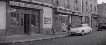 Movie still from “Shoot the Piano Player” (1960), directed by François Truffaut – An old photo of people on the sidewalk of a street; Extreme Wide shot, High angle