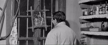 Movie still from “Shoot the Piano Player” (1960), directed by François Truffaut – A man looking into a broken window with a reflection of himself in the mirror; Medium shot, Over the shoulder angle