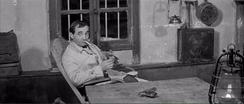 Movie still from “Shoot the Piano Player” (1960), directed by François Truffaut – A man sitting at a table smoking a cigarette; Medium shot, High angle