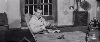 Movie still from “Shoot the Piano Player” (1960), directed by François Truffaut – A black and white photo of a man sitting at a table smoking a cigarette; Medium shot, High angle