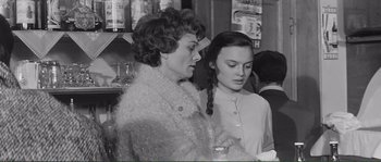 Movie still from “Shoot the Piano Player” (1960), directed by François Truffaut – Two women standing next to each other at a bar; Medium shot, Over the shoulder angle