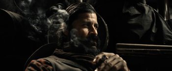 Movie still from “Godless” (2017), directed by Scott Frank – A man with long hair and a beard smoking a pipe; Close Up shot, Low angle