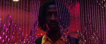Movie still from “Showgirls” (1995), directed by Paul Verhoeven – A man standing in front of a string of beads; Close Up shot, Low angle