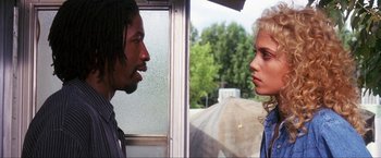 Movie still from “Showgirls” (1995), directed by Paul Verhoeven – A man and a woman standing next to each other in front of a window; Close Up shot, Over the shoulder angle