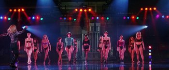 Movie still from “Showgirls” (1995), directed by Paul Verhoeven – A group of women in bathing suits on a stage; Wide shot, Low angle