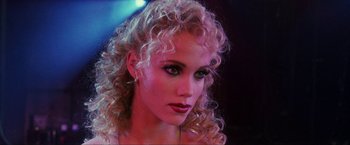 Movie still from “Showgirls” (1995), directed by Paul Verhoeven – A person with curly blonde hair; Close Up shot, Over the shoulder angle