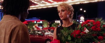 Movie still from “Showgirls” (1995), directed by Paul Verhoeven – A woman with a bouquet of roses in her hand; Medium shot, Over the shoulder angle