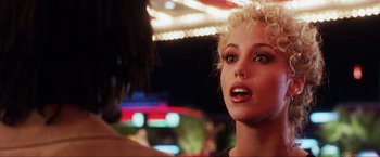 Movie still from “Showgirls” (1995), directed by Paul Verhoeven – A person in a booth with lights in the background; Close Up shot, Over the shoulder angle