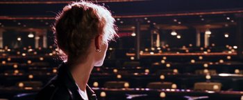 Movie still from “Showgirls” (1995), directed by Paul Verhoeven – A woman is looking into the distance in a theater; Close Up shot, Over the shoulder angle