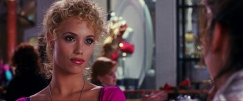 Movie still from “Showgirls” (1995), directed by Paul Verhoeven – A beautiful young woman with a curly blonde hair and a pink shirt; Close Up shot, Over the shoulder angle