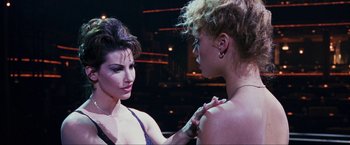 Movie still from “Showgirls” (1995), directed by Paul Verhoeven – Two women one of whom is wearing a necklace and one of whom is wearing a necklace; Close Up shot, Over the shoulder angle