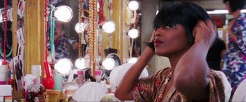 Movie still from “Showgirls” (1995), directed by Paul Verhoeven – A woman sitting in front of a mirror in front of lights; Close Up shot, Over the shoulder angle