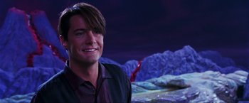 Movie still from “Showgirls” (1995), directed by Paul Verhoeven – A man smiling for the camera in front of a purple background; Close Up shot, Over the shoulder angle