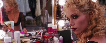 Movie still from “Showgirls” (1995), directed by Paul Verhoeven – A woman sitting in front of a table with makeup on it; Close Up shot, Over the shoulder angle