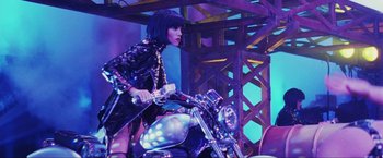 Movie still from “Showgirls” (1995), directed by Paul Verhoeven – A woman in a black outfit on top of a motorcycle; Wide shot, Low angle