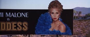 Movie still from “Showgirls” (1995), directed by Paul Verhoeven – A painting of a woman in a blue dress; Close Up shot, Low angle