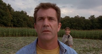 Movie still from “Signs” (2002), directed by M. Night Shyamalan – A man and a woman standing next to each other in a field; Close Up shot, Low angle