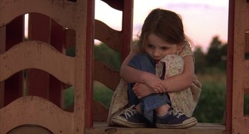 Movie still from “Signs” (2002), directed by M. Night Shyamalan – A little girl sitting on the ground with her hands on her knees; Close Up shot, High angle
