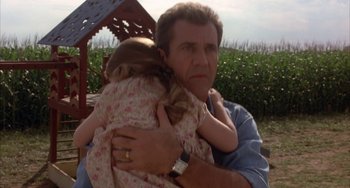 Movie still from “Signs” (2002), directed by M. Night Shyamalan – A person holding a child; Medium shot, Low angle