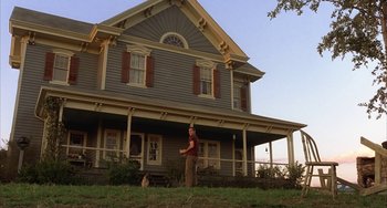 Movie still from “Signs” (2002), directed by M. Night Shyamalan – A man standing in front of a house with a dog; Wide shot, Low angle