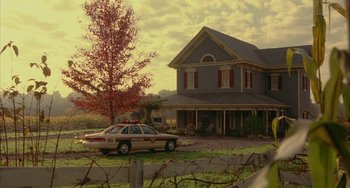 Movie still from “Signs” (2002), directed by M. Night Shyamalan – A police car parked in front of a house; Extreme Wide shot, Low angle