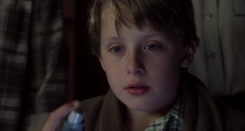 Movie still from “Signs” (2002), directed by M. Night Shyamalan – A young boy holding a cell phone in his hand; Close Up shot, High angle