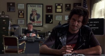 Movie still from “Signs” (2002), directed by M. Night Shyamalan – A man sitting at a table in front of another man; Medium shot, Over the shoulder angle