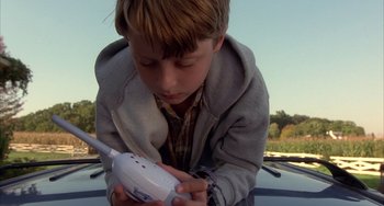 Movie still from “Signs” (2002), directed by M. Night Shyamalan – A young boy is holding a remote control in his hands; Close Up shot, Low angle